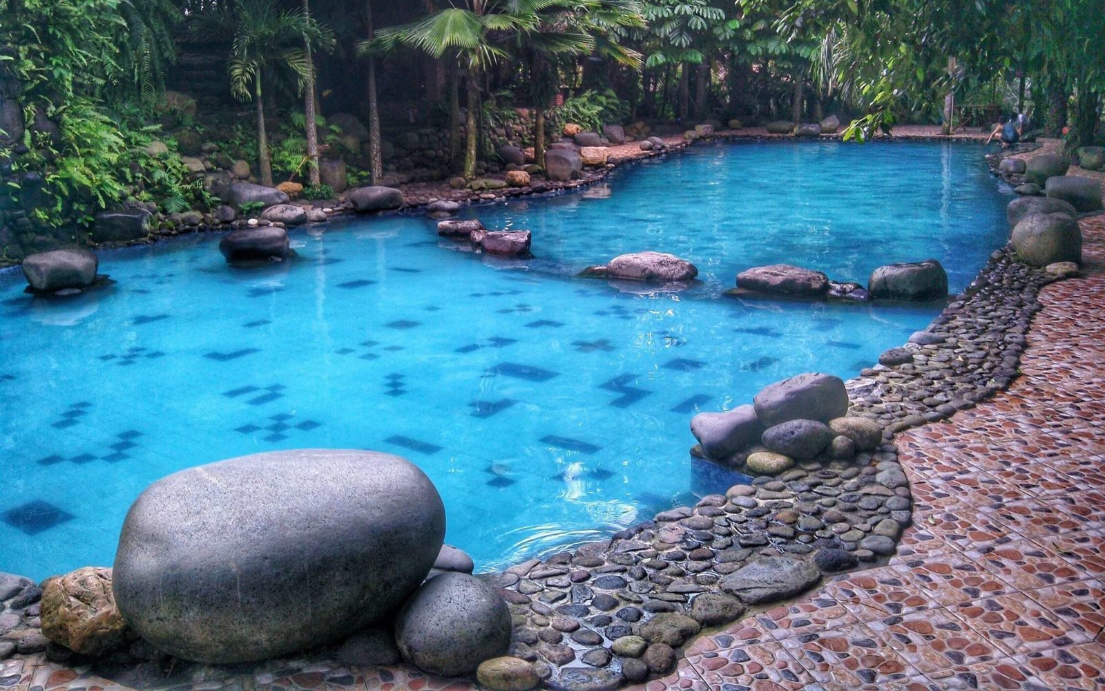 kolam renang dikelilingi taman hijau watu gunung