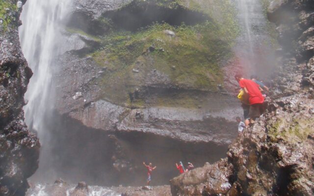 wisatawan yang sedang mandi dan berenang di air terjun