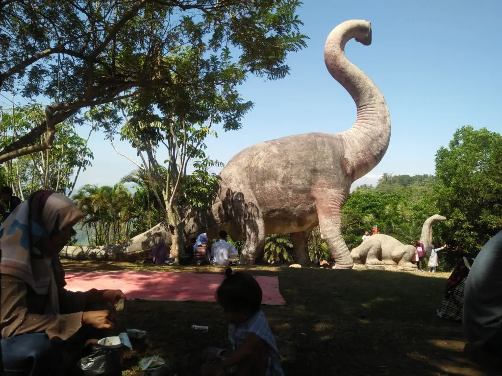 pengunjung sedang berpiknik di taman dinosaurus