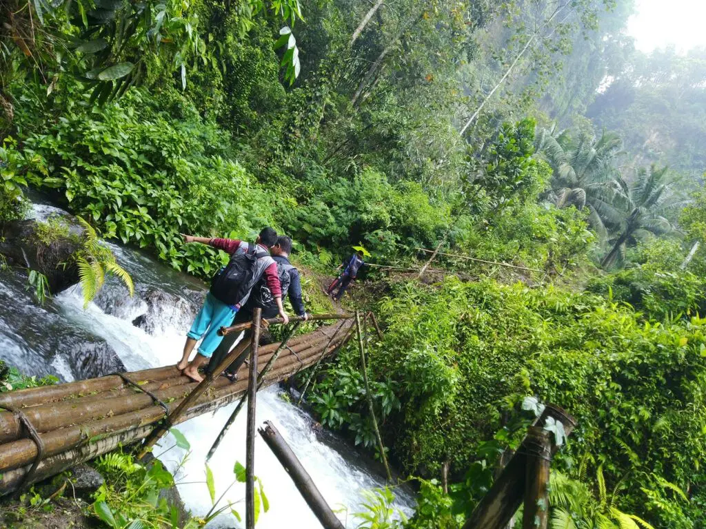 Pengunjung melewati jembatan bambu