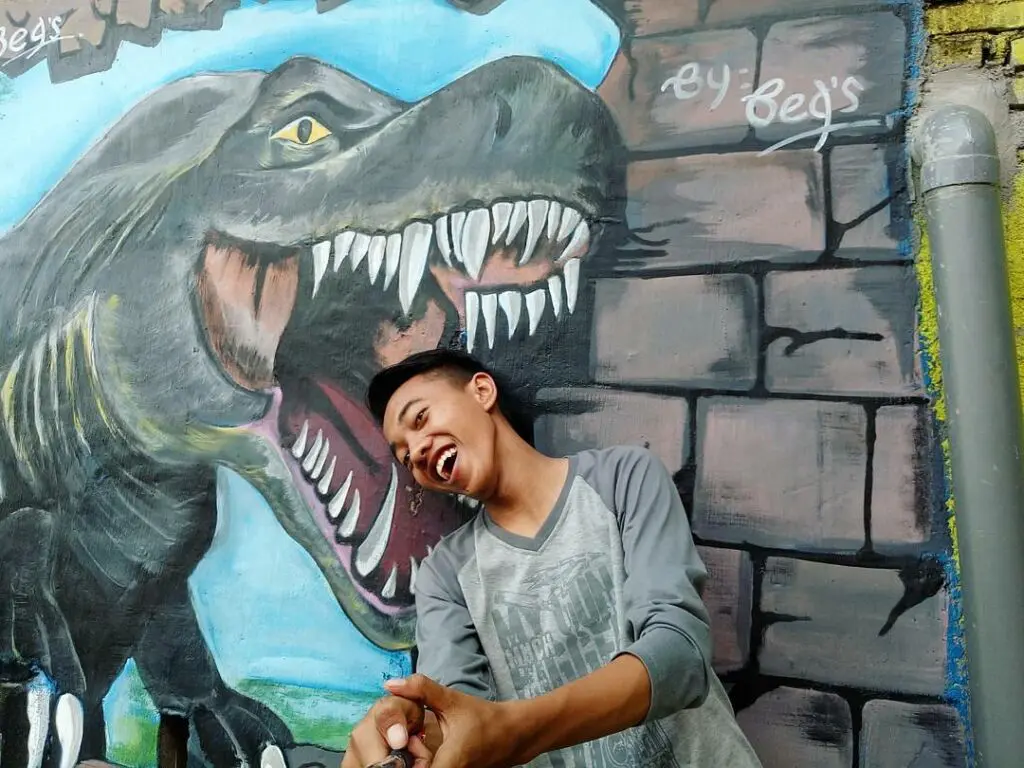 Berfoto dengan Mural Dinosaurus di Kampung Tridi Malang. Foto: instargram / babangirman