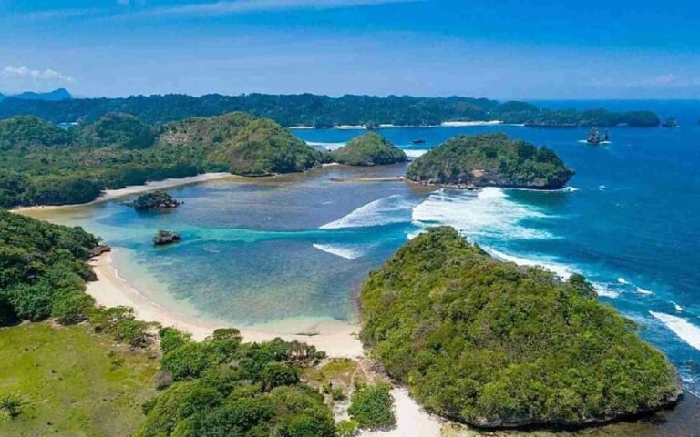 bentang alam bukit hijau dan pasir putih pantai teluk asmara