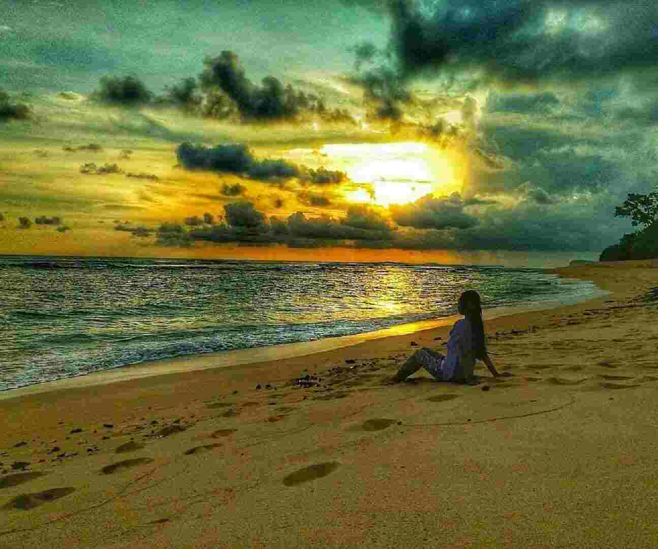 wisatawan menikmati sunset di tepi pantai