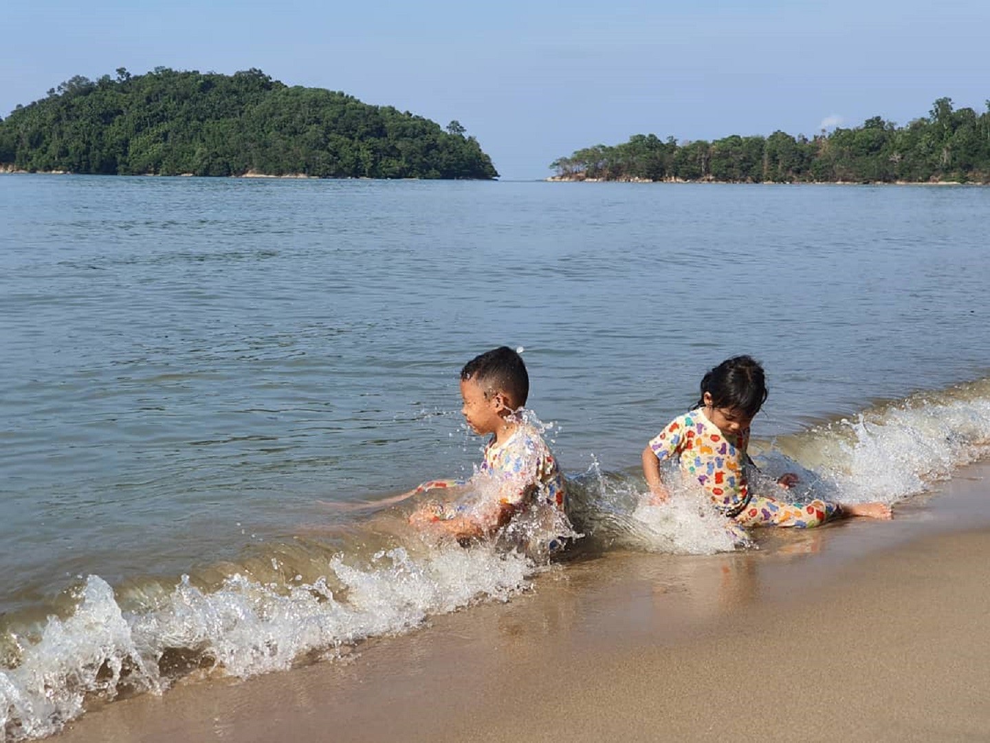 anak-anak sedang bermain air di tepi pantai