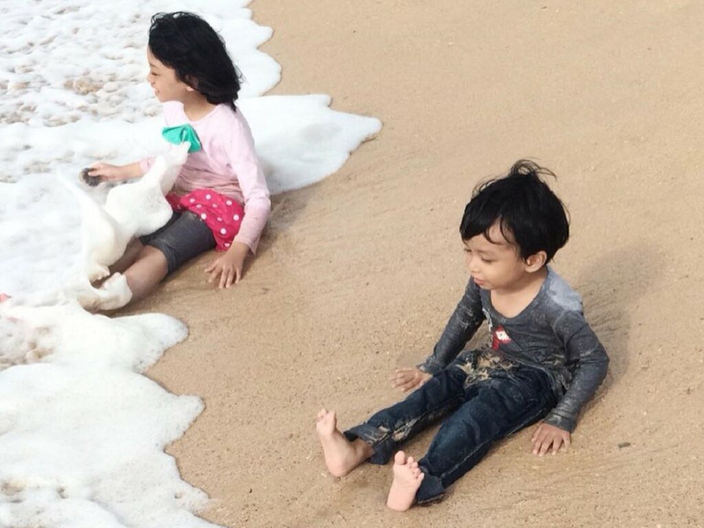 anak-anak sedang bermain air di tepi pantai