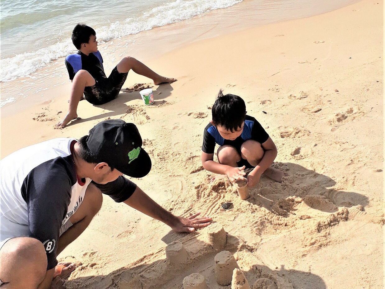 wisatawan bermain pasir di tepi pantai pasir panjang
