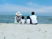 Keluarga tengah berfoto bersama berlatarkan birunya langit dan beralaskan putihnya pasir Sri Mersing
