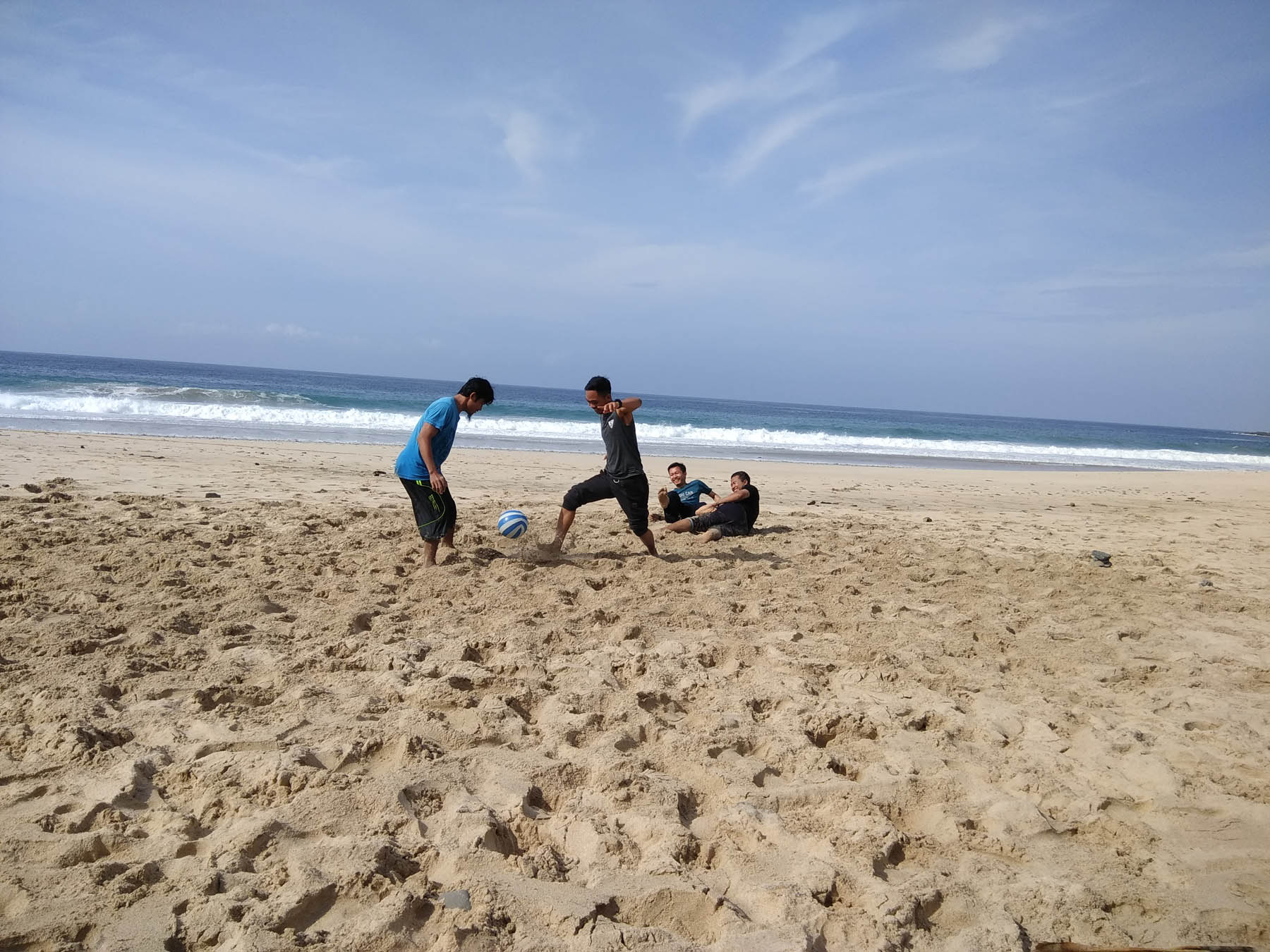 wisatawan sedang bermain sepak bola di tepi pantai