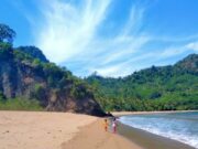 bentang alam pantai yang dikelilingi perbukitan hijau