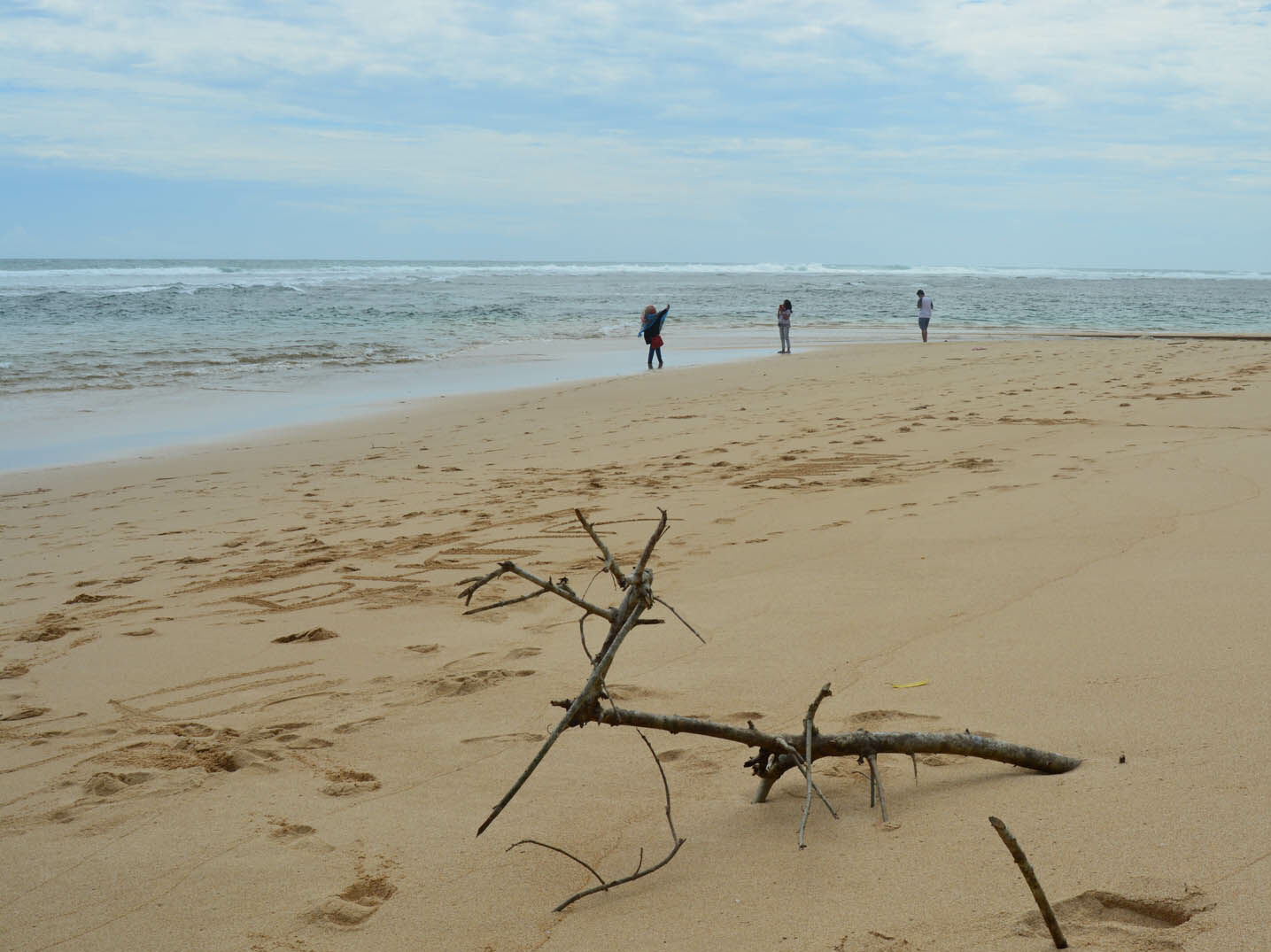 wisatawan bermain di tepi pantai