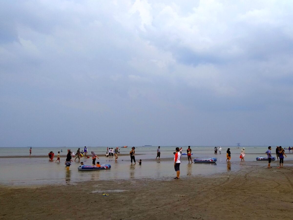 ramai pengunjung bermain di tepi pantai