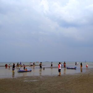 ramai pengunjung bermain di tepi pantai