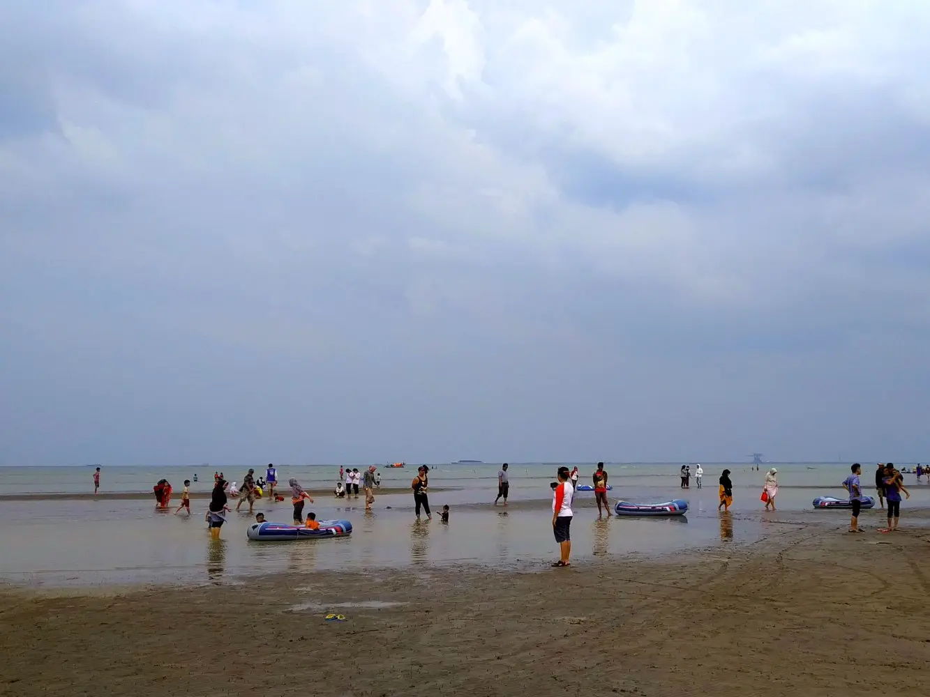 ramai pengunjung bermain di tepi pantai