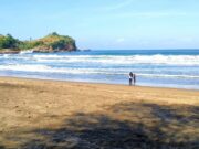 Area pantai berpasir putih halus serta ombak yang tenang di tepi pantai