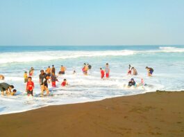 wisatawan bermain di tepi pantai