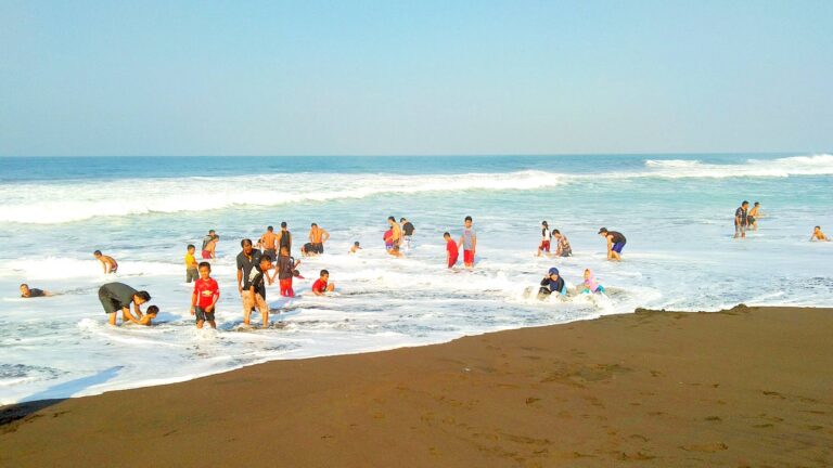 wisatawan bermain di tepi pantai