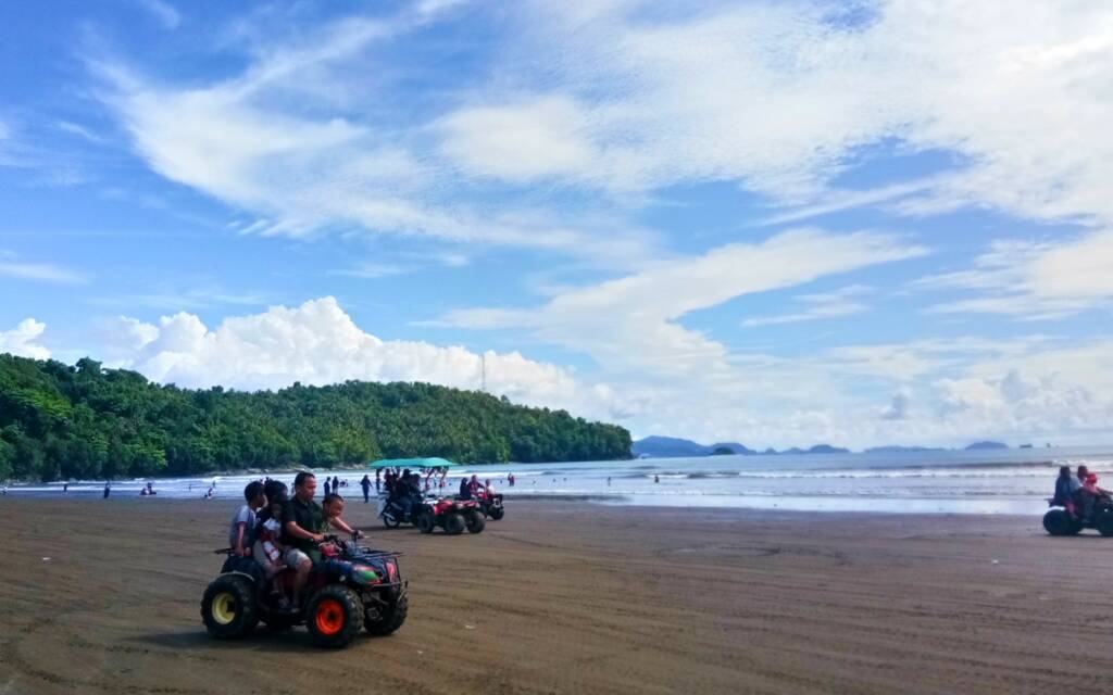 Pengunjung yang sedang bermain ATV di tepi pantai