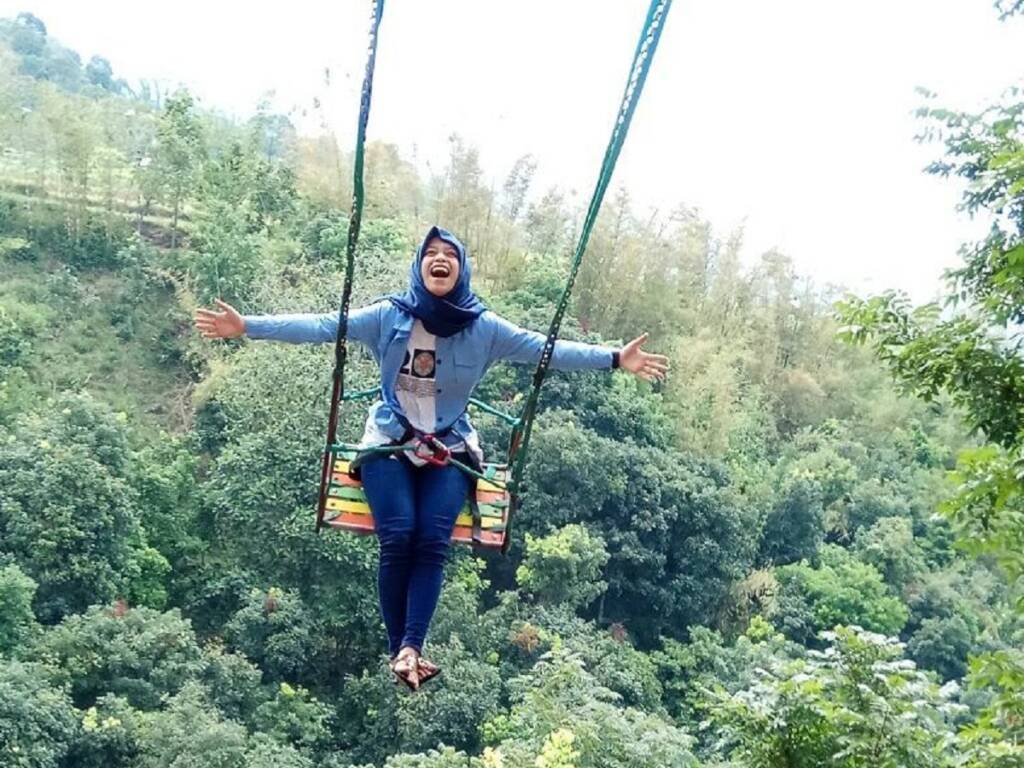 Mengayun tinggi di udara pada wahana penantang adrenalin di Claket Adventure Park Mojokerto.