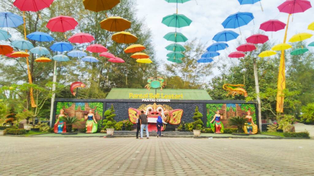 Payung warna-warni di depan landmark Pantai Bali Lestari