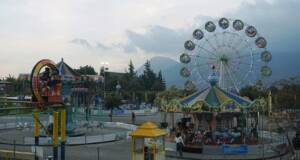 Menikmati serunya wahana permainan Taman Ghanjaran berlatar pemandangan pegunungan di Mojokerto.