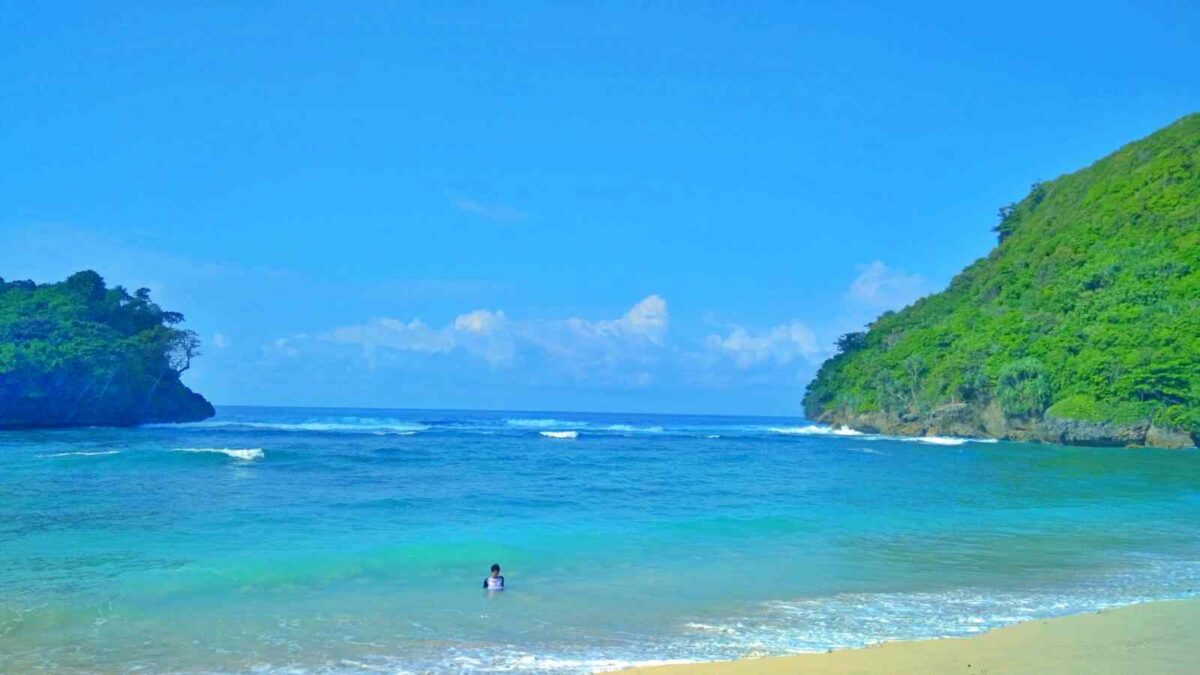 wisatawan bermain di laut biru pantai kwaru