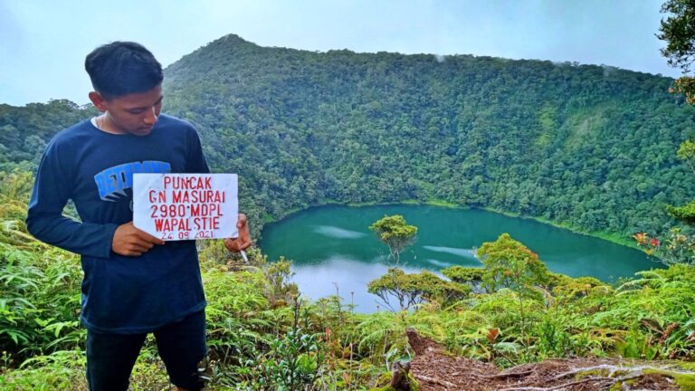 Puncak Gunung Masurai berlatar danau hijau