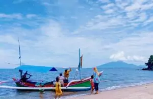 Pengunjung akan naik perahu di Pantai Tampora