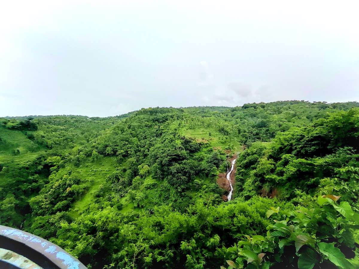 Perbukitan hijau dan air terjun dilihat dari Arak-arak Bondowoso