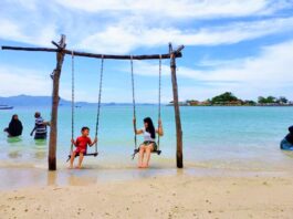 wisatawan bermain ayunan di Pantai Mutun