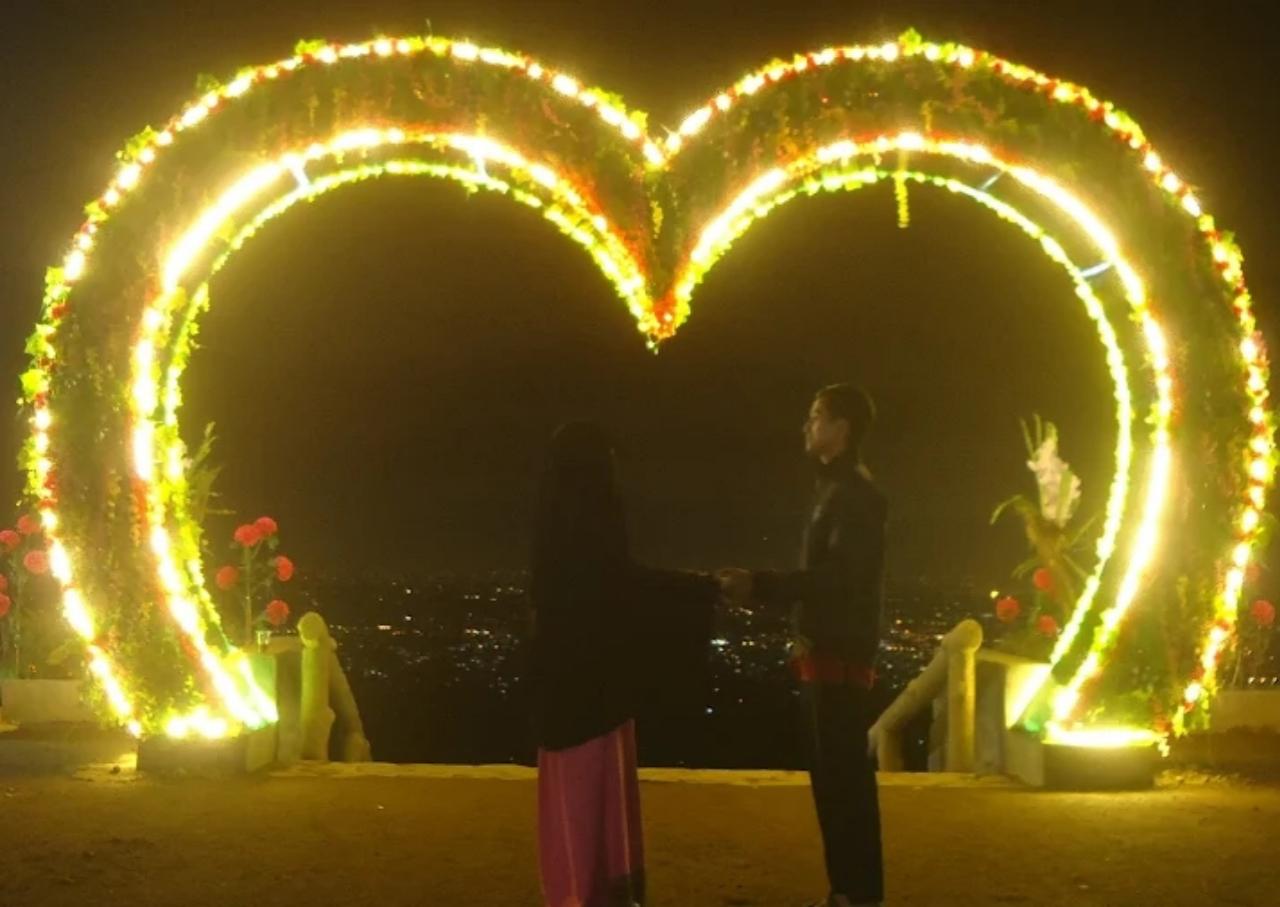 dua orang berdiri di depan spot love wisata Kampoeng Salaka