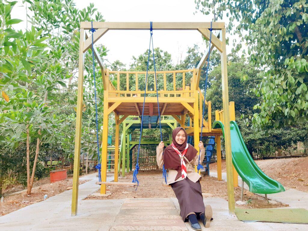 Seorang wanita berayun di arena playground Kampung Kahuripan Cirangkong.