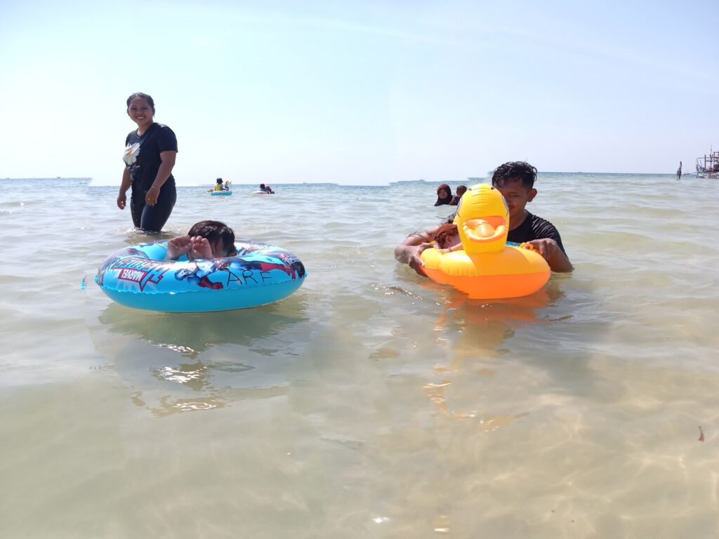 Dua orang anak kecil sedang berenang di Pantai Kampung Prau.