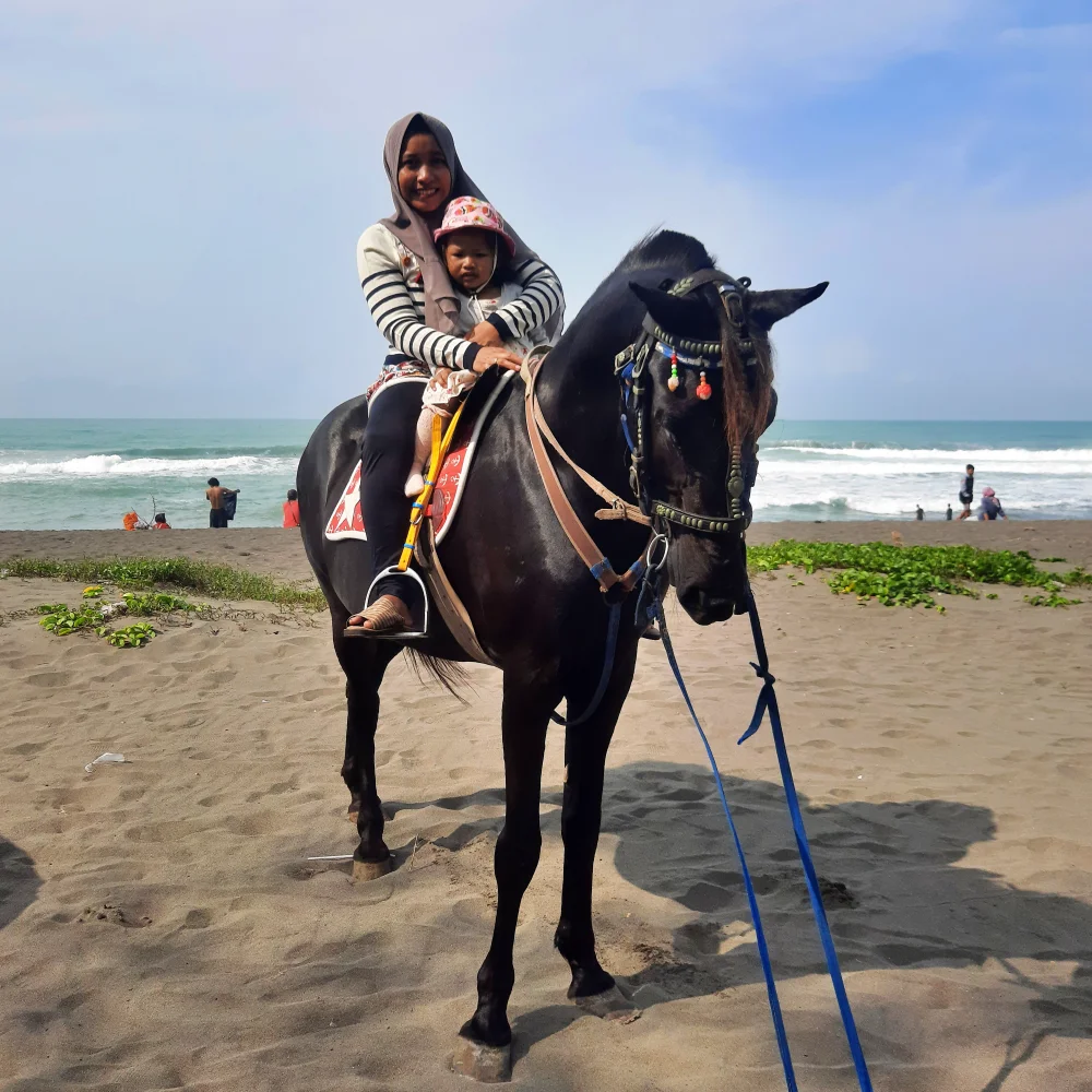 Wisatawan menunggang kuda di atas pasir Pantai Lumut