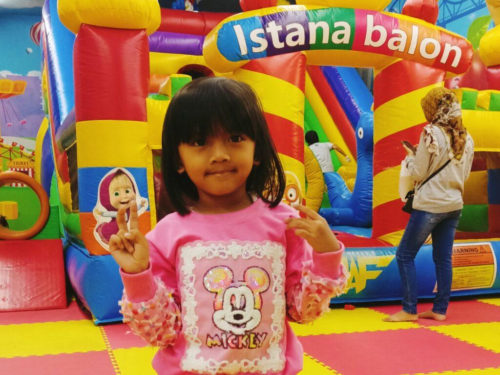 Anak perempuan berfoto di istana balon Radja Toys.