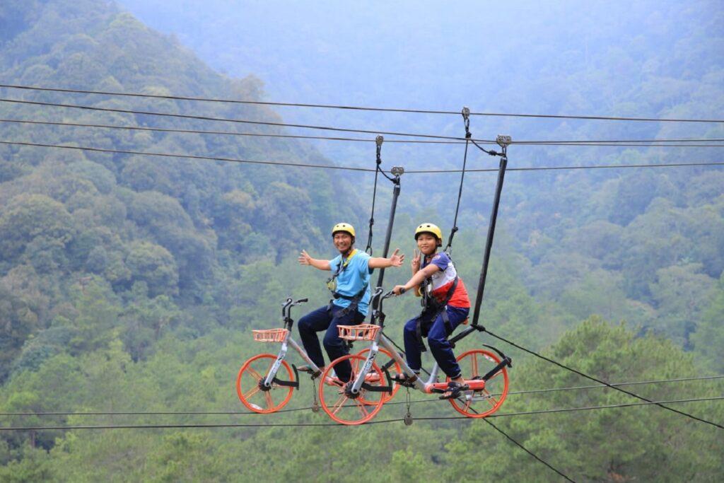 Dua orang laki-laki mencoba wahana sky bike di wisata alam sevillage.