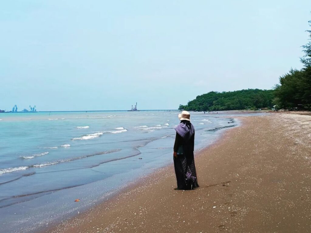 seorang wanita berdiri di tepi Pantai Sigandu.