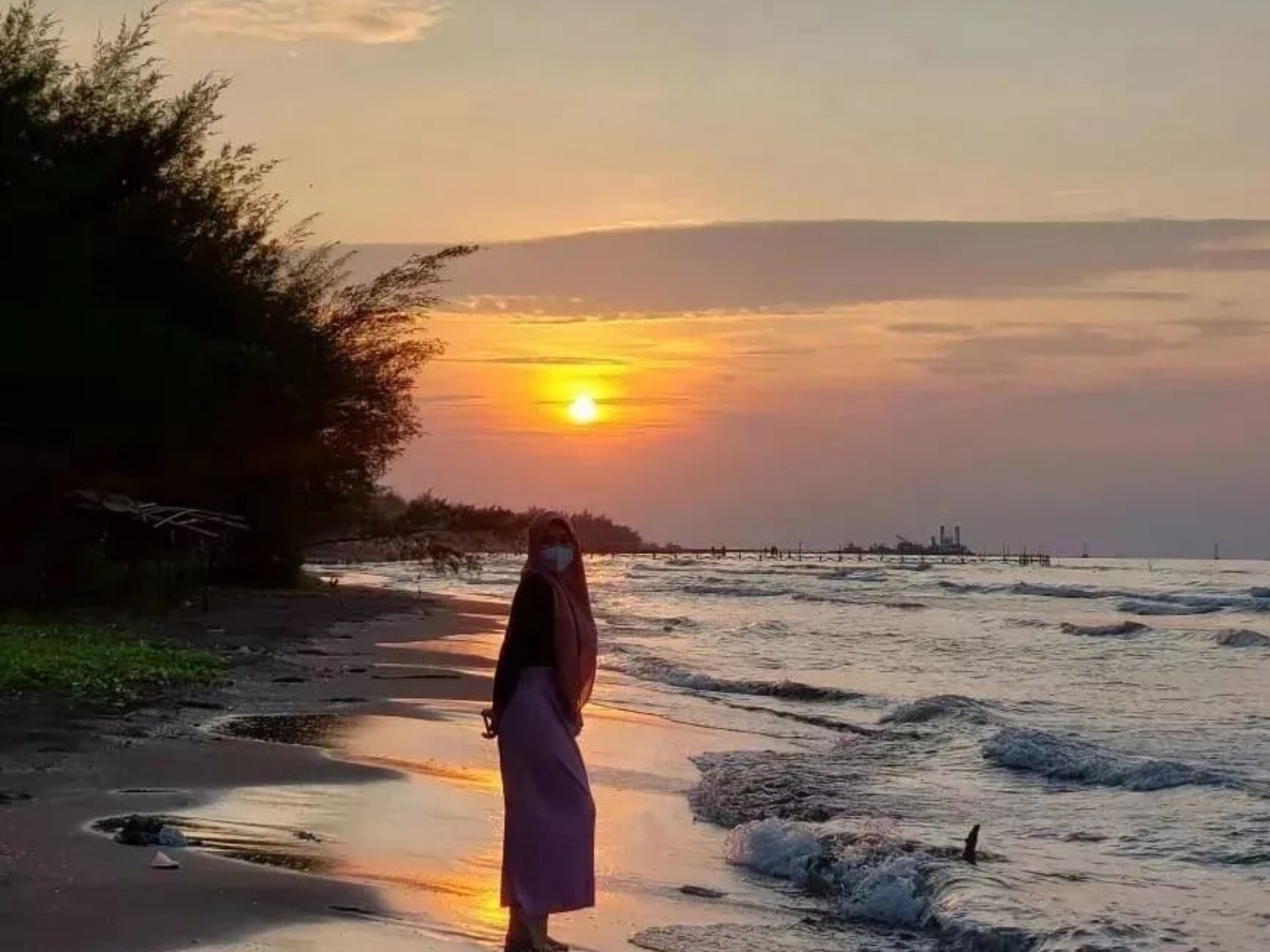 Seorang wanita foto dengan background sunset di Pantai Sigandu Batang.