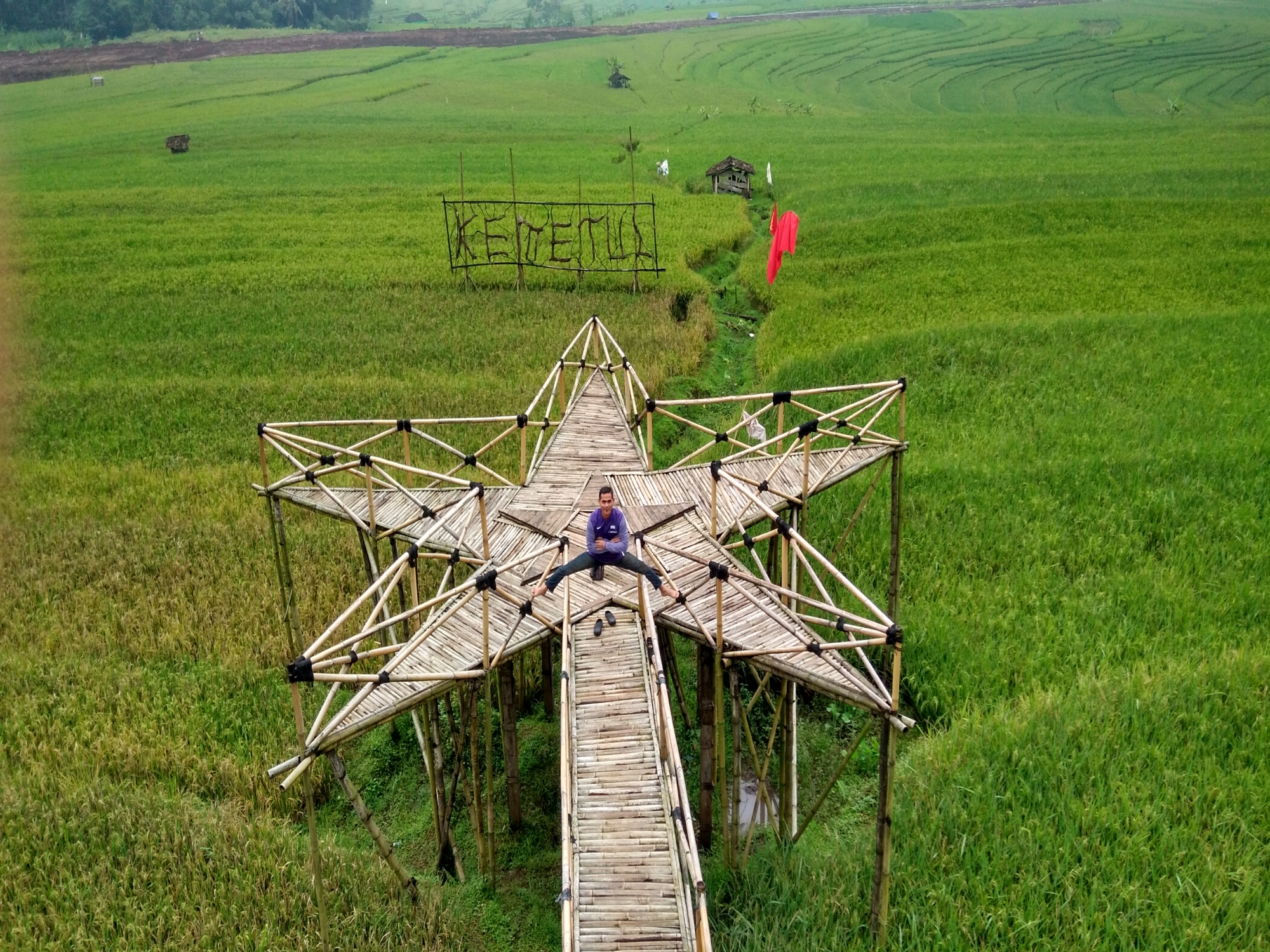 Seorang pria berfoto di atas jembatan bambu berbentuk bintang di Desa Wisata Kemetul.