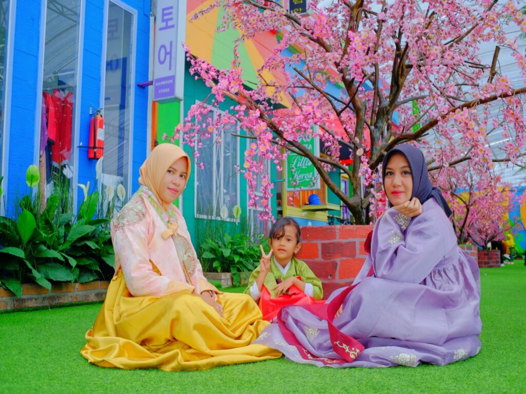 Tiga orang wanita foto di spot little korea Taman Bunga Celosia dengan mengenakan pakaian hanbok.