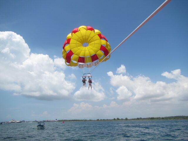 Permainan watersport di Tanjung Benoa Beach salah satunya parasailing yang ditarik boat